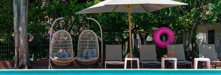 Pool mit zwei Hängesesseln und Liegestühlen unter Sonnenschirm