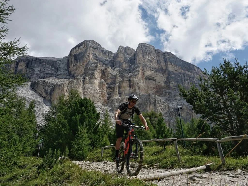 Mountain biker su sentiero roccioso con alte pareti di montagna sullo sfondo