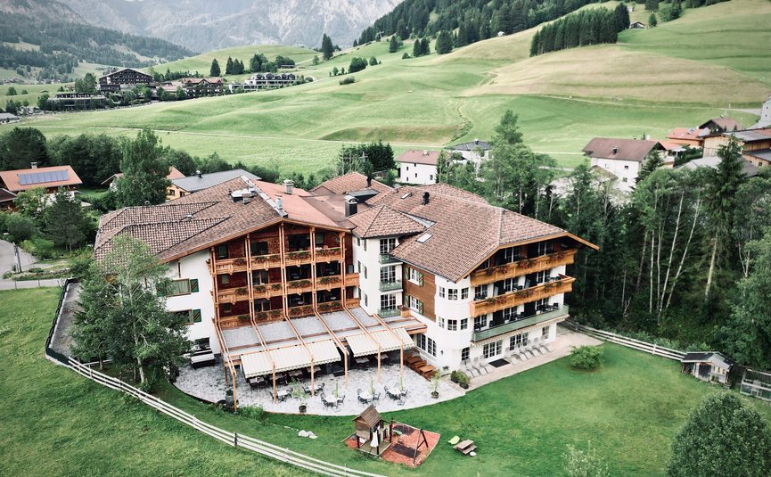 Mountain hotel with terrace, playground, and green meadows in alpine scenery