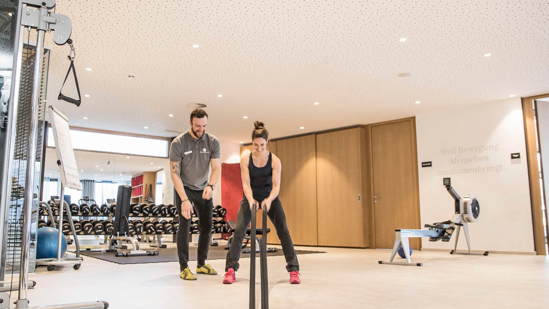 Frau trainiert mit Schlachtseilen im Fitnessstudio mit Trainer