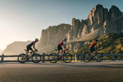 Drei Radfahrer fahren auf Bergstraße mit Felsen im Hintergrund