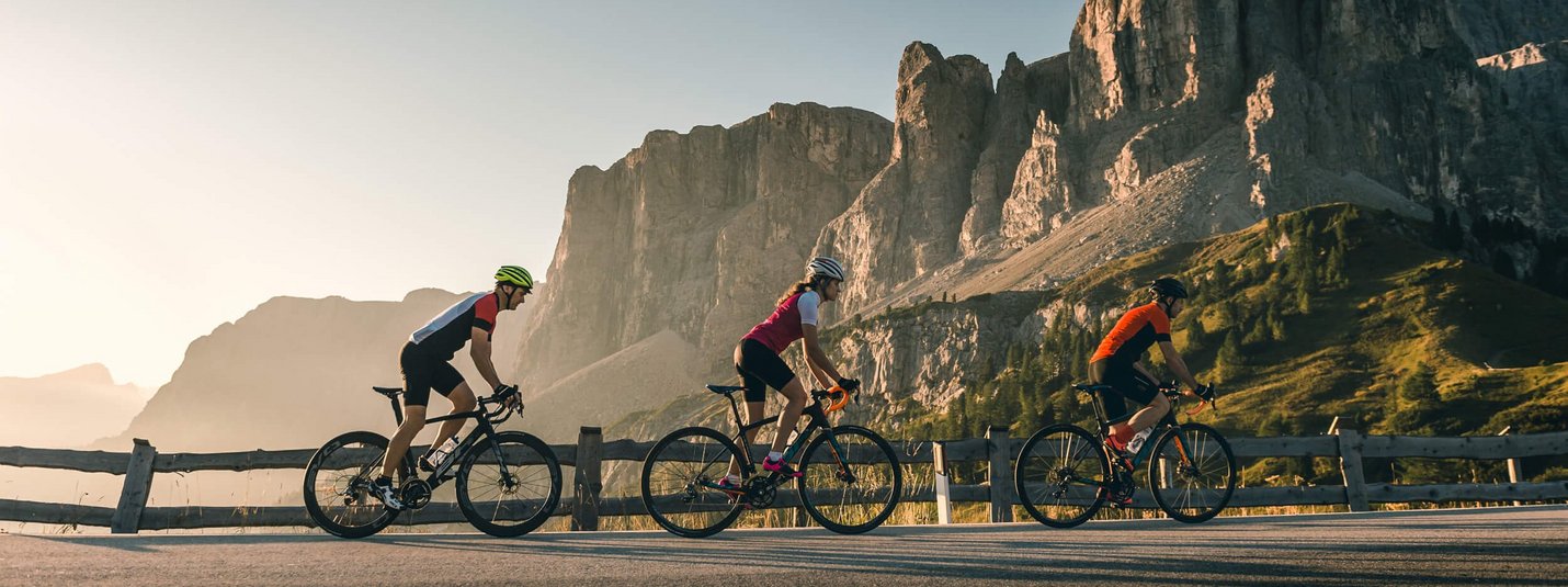 Drei Radfahrer fahren auf Bergstraße mit Felsen im Hintergrund