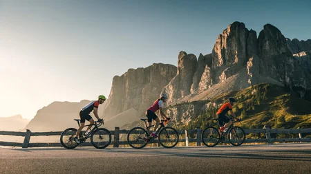 Warum Alta Badia auf jede Roadbike-Bucket-List gehört © Molography Drei Radfahrer fahren auf Bergstraße mit Felsen im Hintergrund