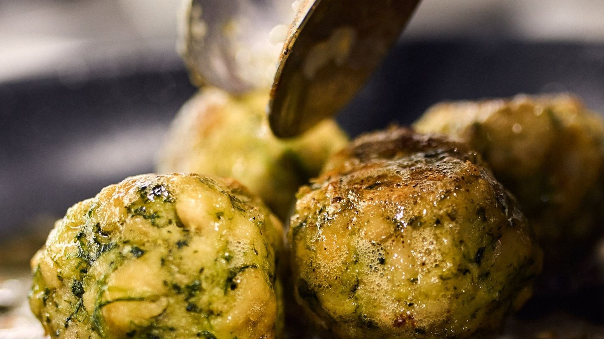 Spinatklöße braten in einer Pfanne mit einem Löffel