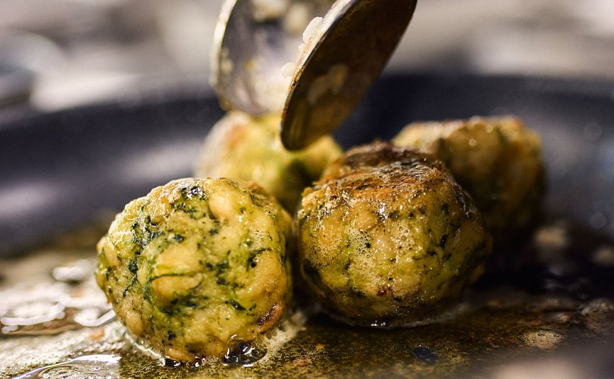 Spinatklöße braten in einer Pfanne mit einem Löffel