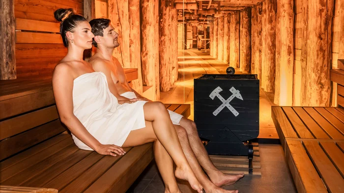 Mann und Frau entspannen zusammen in einer Holzsauna mit warmem Licht