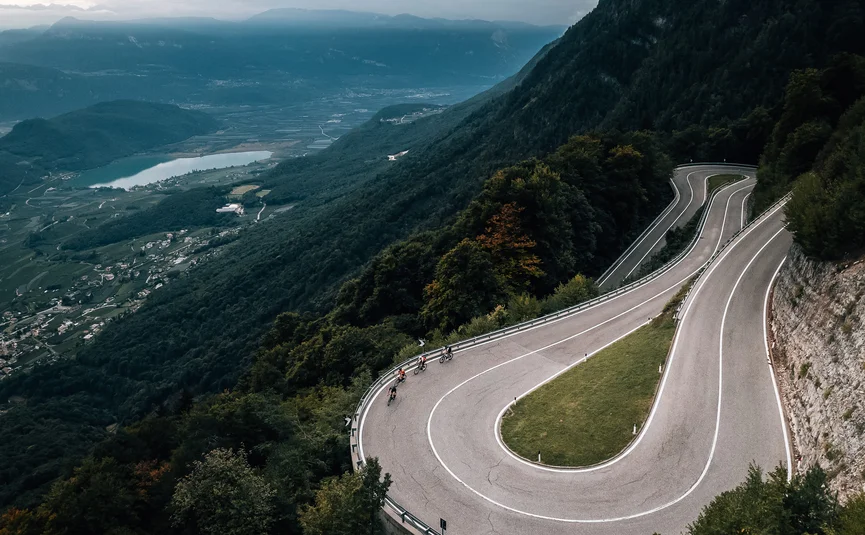 Radfahrer fahren eine enge Serpentinen-Straße durch bewaldete Berge