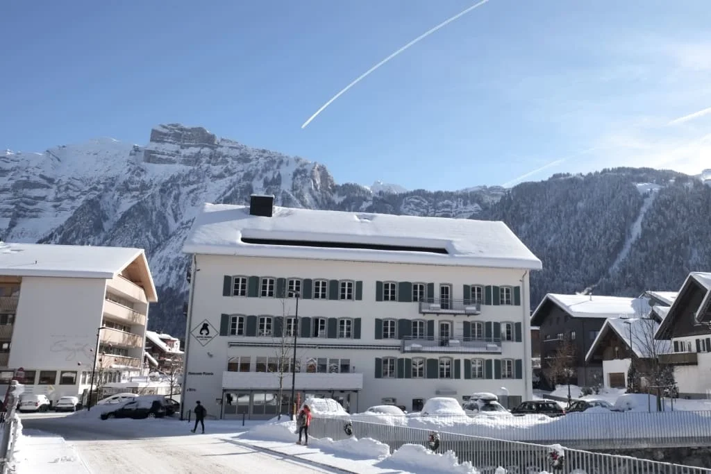 Aktion Kinderschnee Sneeuwbedekt huis in winters stadje met bergen en blauwe lucht