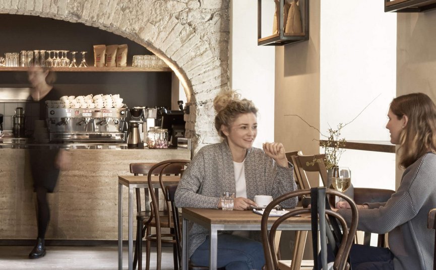 Two women chatting in a café with drinks on the table