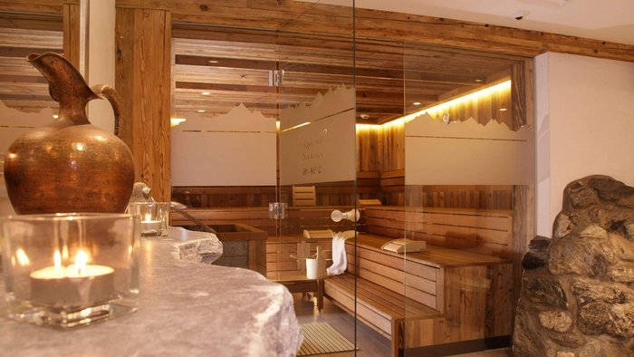 Saunaraum mit Glastür, Holzvertäfelung und Kerzenbeleuchtung