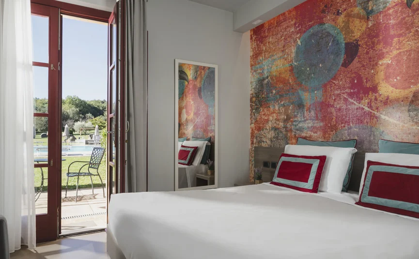 Modernes Schlafzimmer mit buntem Wandbild und Terrasse mit Blick auf einen Pool