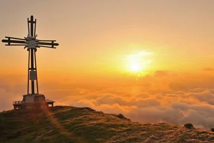 Houten kruis op bergtop bij zonsopgang boven de wolken