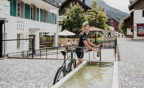 Klub Frischluft Paket Frau mit Rennrad füllt Wasserflasche an Brunnen in Stadt