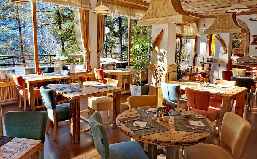 Ristorante accogliente con tavoli di legno, sedie colorate e luce naturale brillante