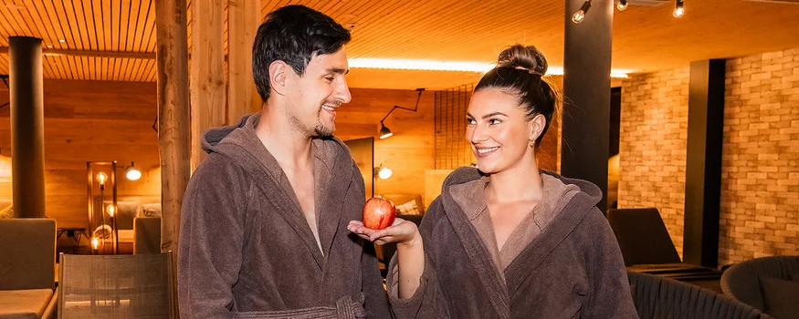 Paar in Bademänteln im Spa, Frau hält einen Apfel