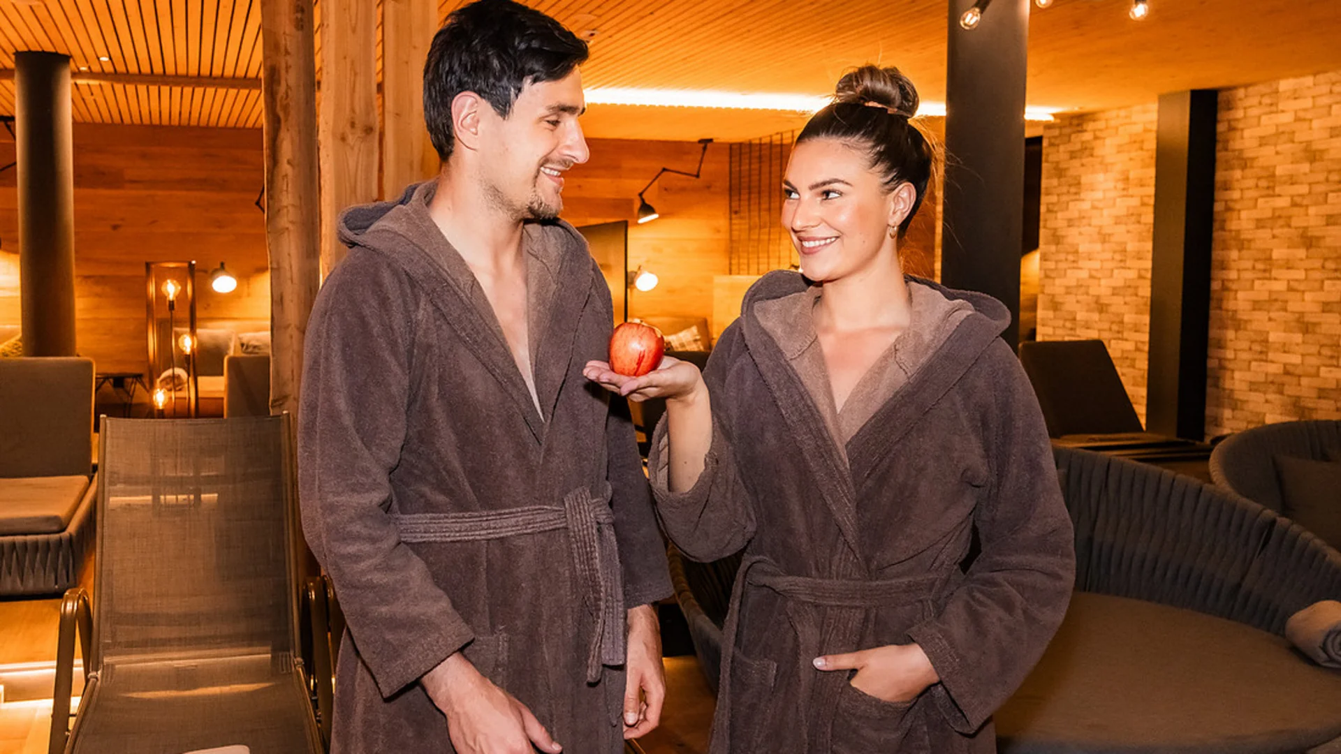 Paar in Bademänteln im Spa, Frau hält einen Apfel