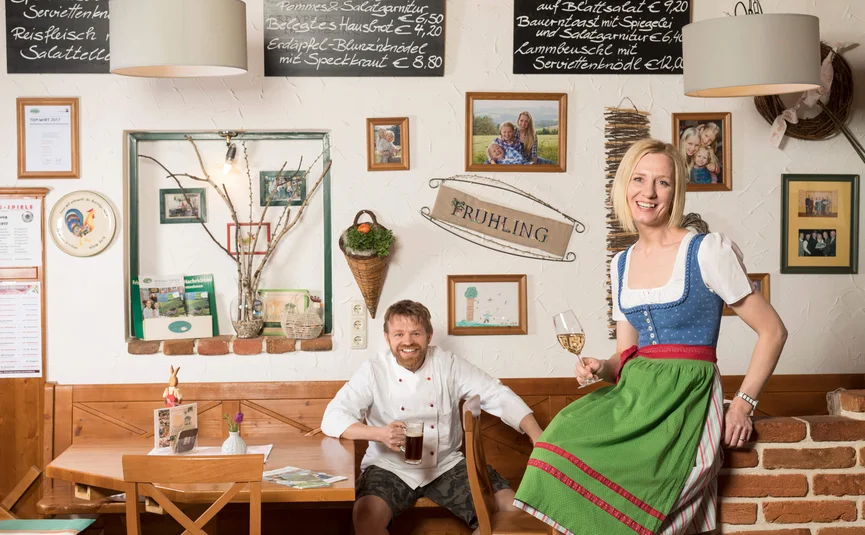 Donna in abito tradizionale e uomo con birra in ristorante rustico
