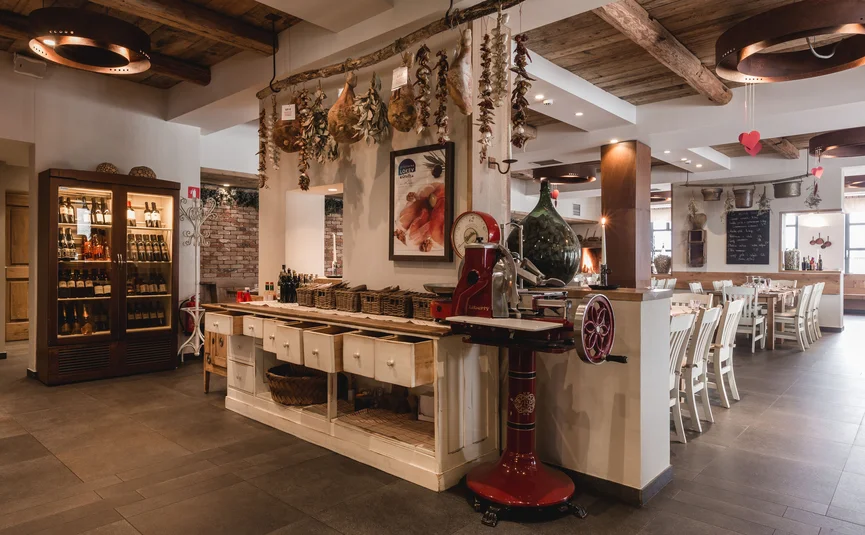 Rustikales Restaurant mit Holzdecke und hängendem Schinken und Gewürzen