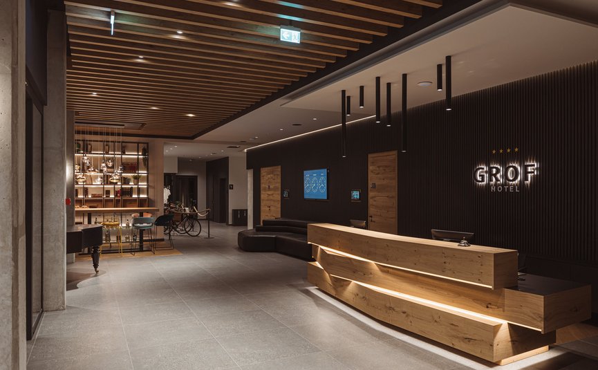 Reception dell'hotel con bancone in legno moderno e area salotto accogliente