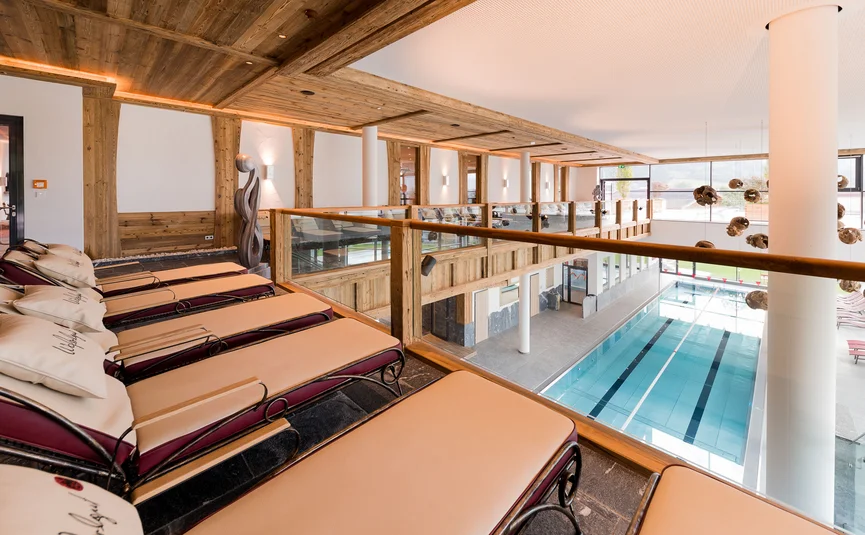 Ontspanningsruimte met ligstoelen en uitzicht op het binnenzwembad in moderne spa