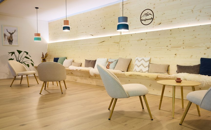 Gemütlicher Wartebereich mit Holzwänden, Stühlen und bunten Kissen