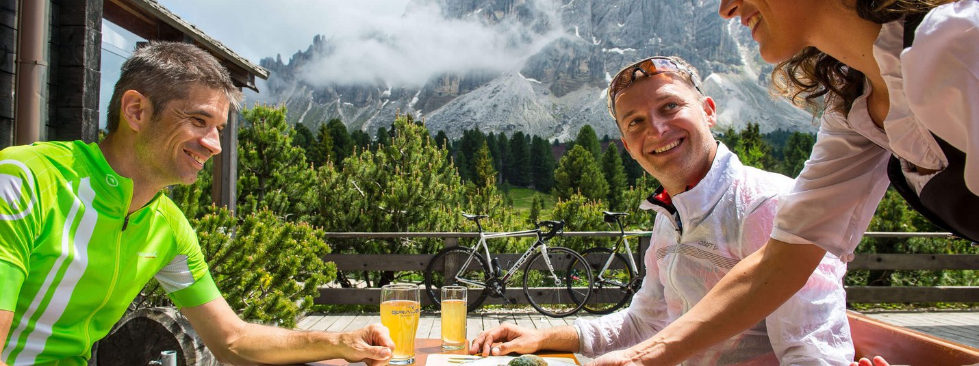 Three cyclists dining outdoors with mountain view