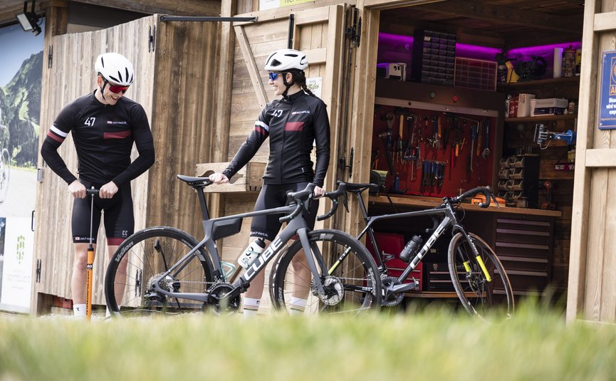 Triathlon & Rennrad Aktivhotel SantaLucia **** © VeloMotion Due ciclisti con caschi e bici da corsa davanti a una officina