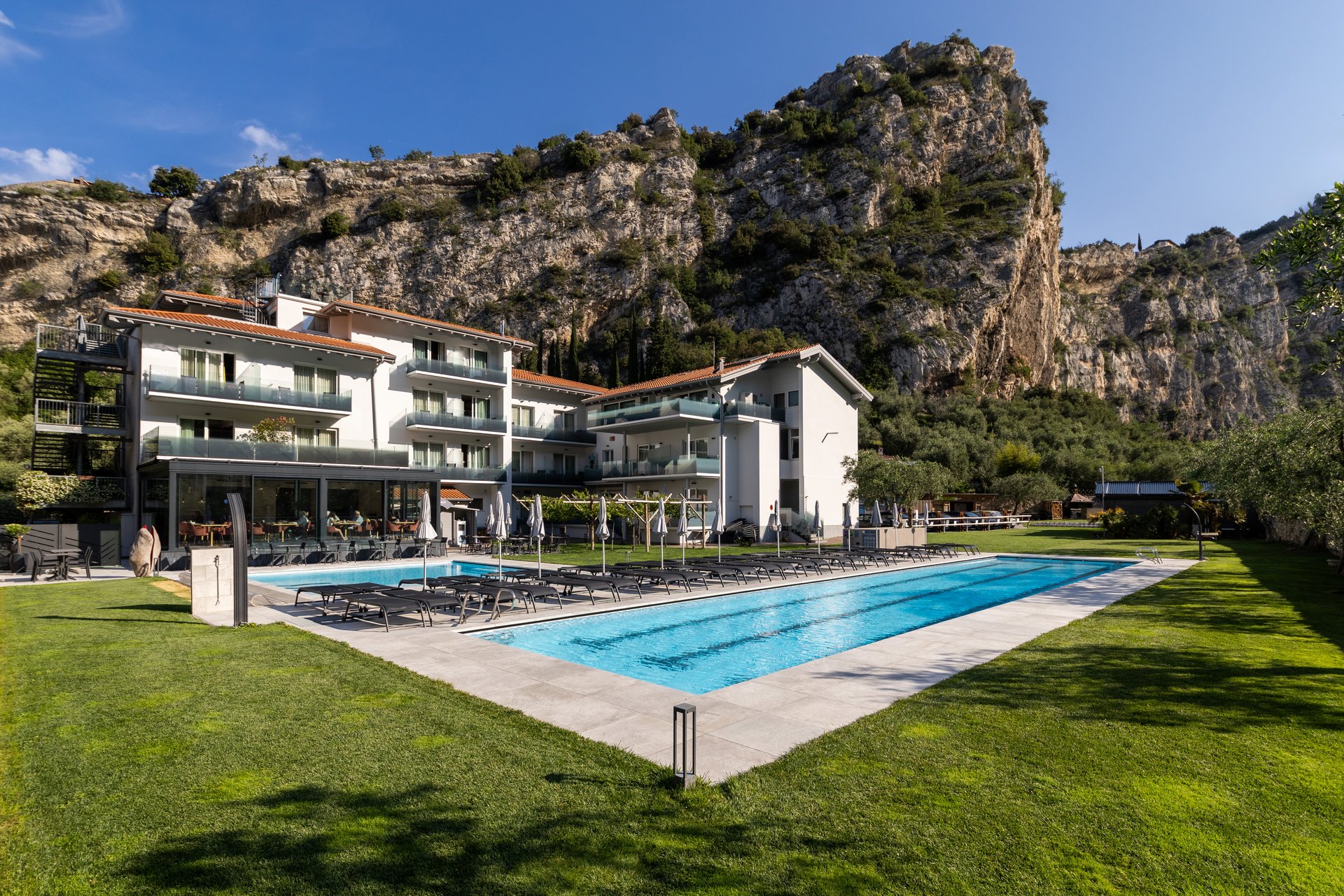 Roadbike Holidays © Fabio Staropoli Hotel mit Außenpool und Liegestühlen vor Felsen unter blauem Himmel