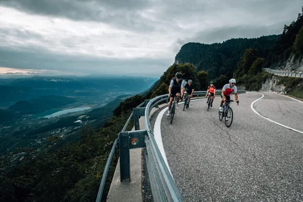 Fahrradfahrer fahren auf einer kurvigen Bergstraße mit Talblick