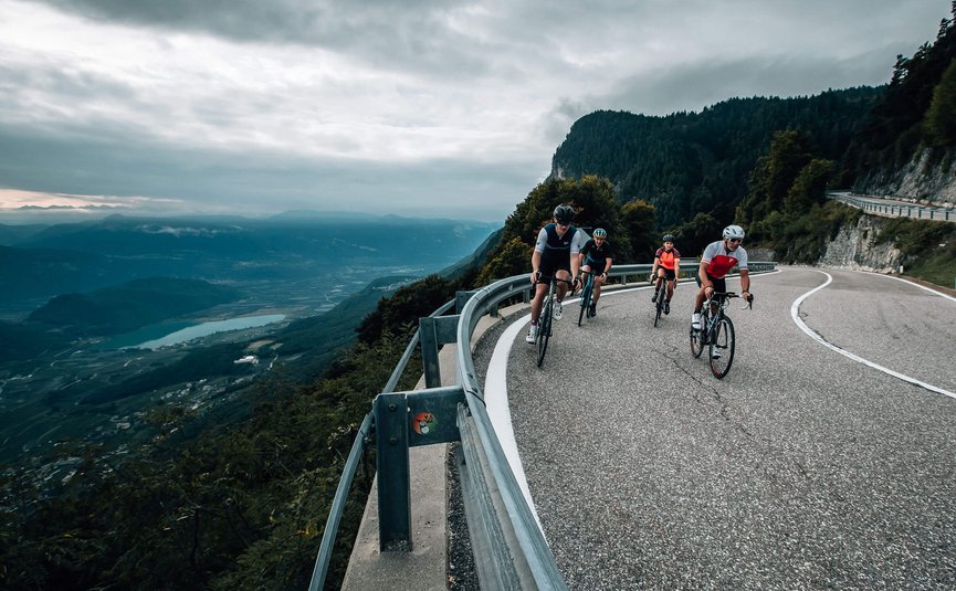 Ciclisti su una strada di montagna curva con vista sulla valle