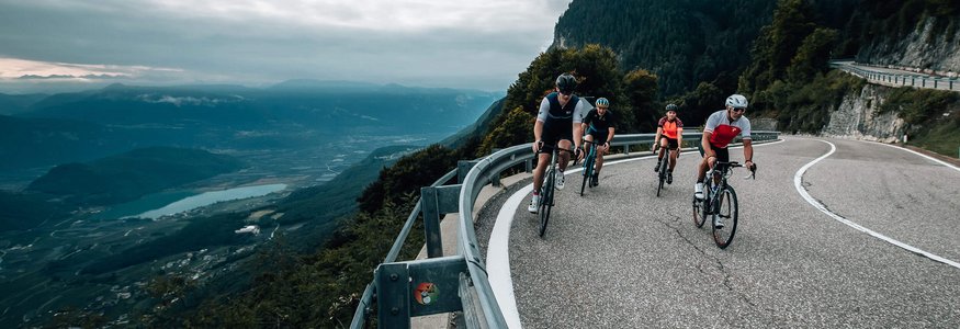 Ciclisti su una strada di montagna curva con vista sulla valle