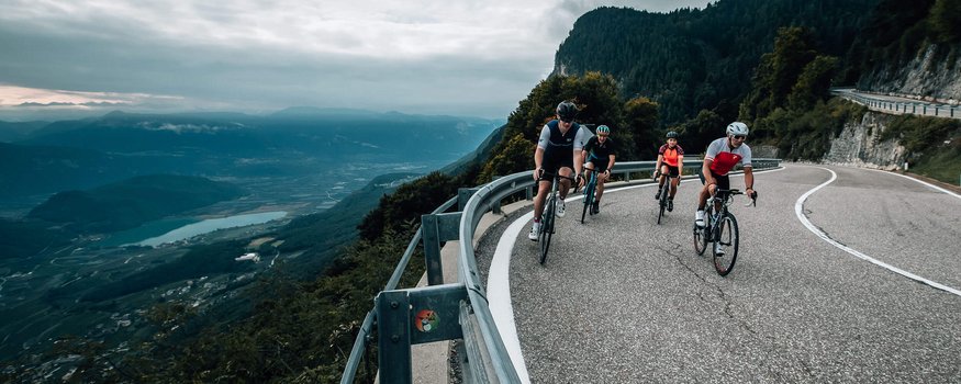 Ciclisti su una strada di montagna curva con vista sulla valle