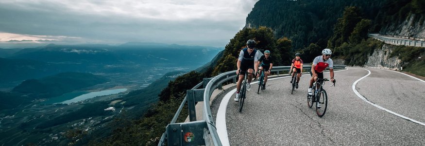 Fahrradfahrer fahren auf einer kurvigen Bergstraße mit Talblick
