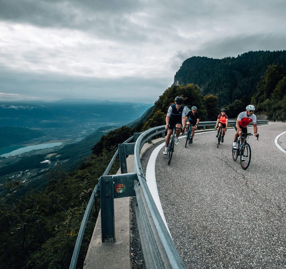 Fahrradfahrer fahren auf einer kurvigen Bergstraße mit Talblick