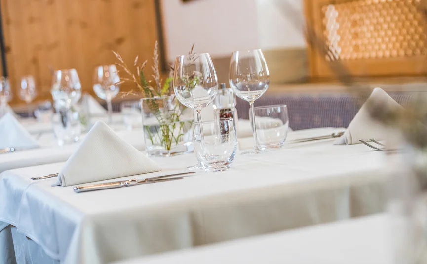 Tisch gedeckt mit weißen Servietten, Gläsern und Besteck in einem Restaurant