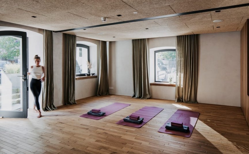 Yoga room with three mats and open door, woman entering the room