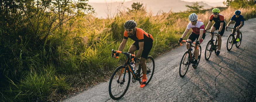 Die schönsten Rennrad-Regionen und Tipps für den Herbst © Alex Moling Vier Radfahrer fahren auf einer bergigen Landstraße bei Sonnenuntergang