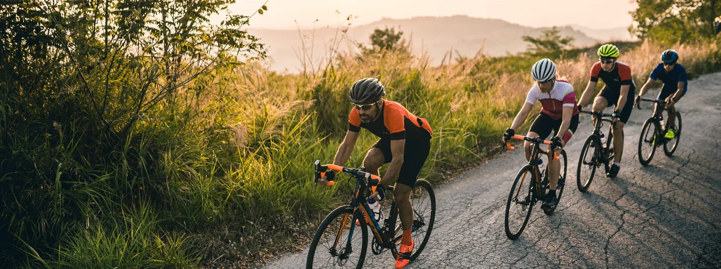 Monte Carpegna © Alex Moling Vier Radfahrer fahren auf einer bergigen Landstraße bei Sonnenuntergang