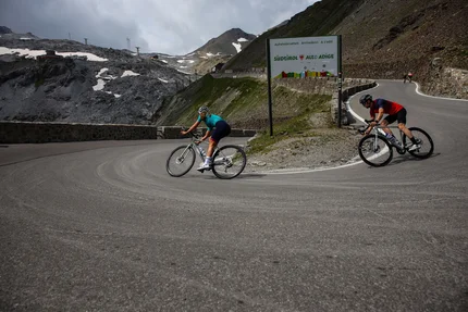 Zwei Radfahrer auf einer Bergstraße nahe einem Südtirol-Schild