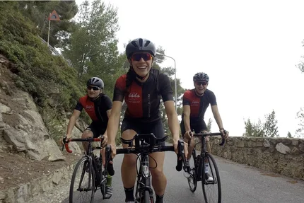 Three cyclists in sportswear riding on a mountain road