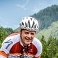 Cyclist riding uphill on winding road in green alpine landscape