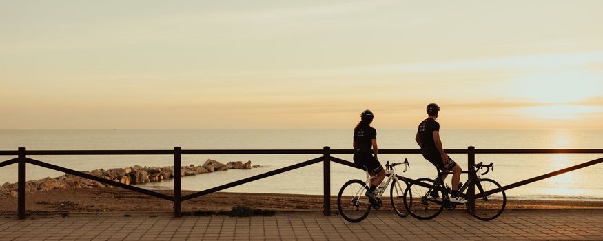 Saisonstart im Natural Village Resort © Alex Moling Zwei Radfahrer blicken bei Sonnenuntergang aufs Meer am Promenadenweg