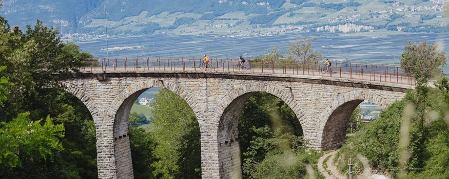 Saisonstart im Teutschhaus © Thomas Monsorno - TV Castelfeder Fahrradfahrer auf einer Steinbrücke mit Bögen in einer grünen Landschaft
