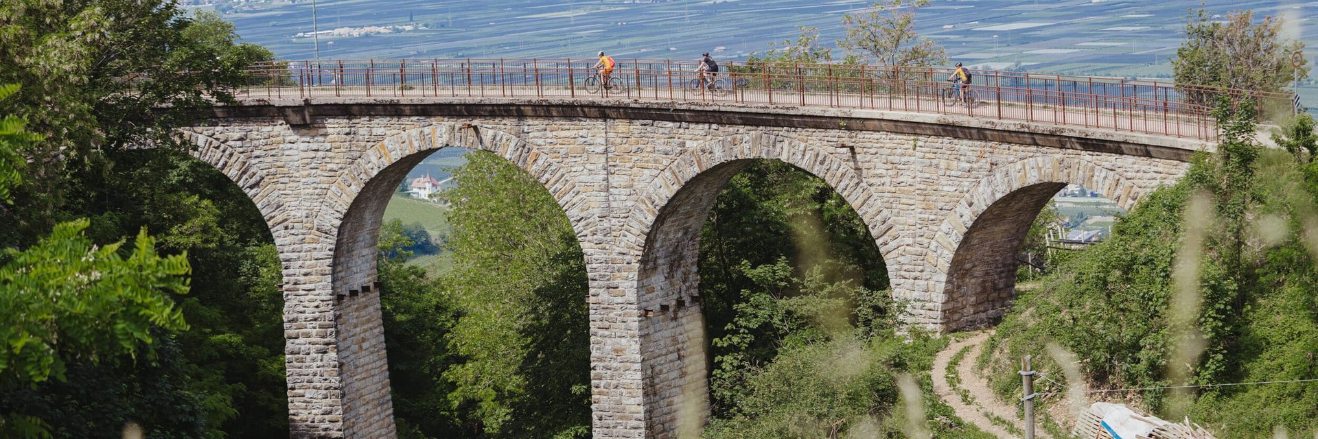 Ciclisti su un ponte ad archi di pietra in una zona verde