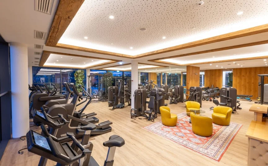 Moderner Fitnessraum mit Trainingsgeräten und gemütlicher Sitzecke