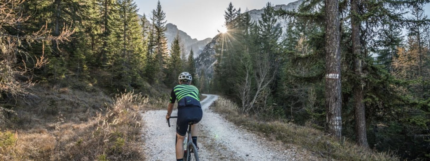 Ciclista su sentiero boschivo al tramonto in montagna