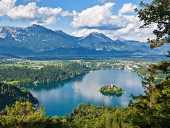 Lake with island and church, surrounded by forest and mountains in the background