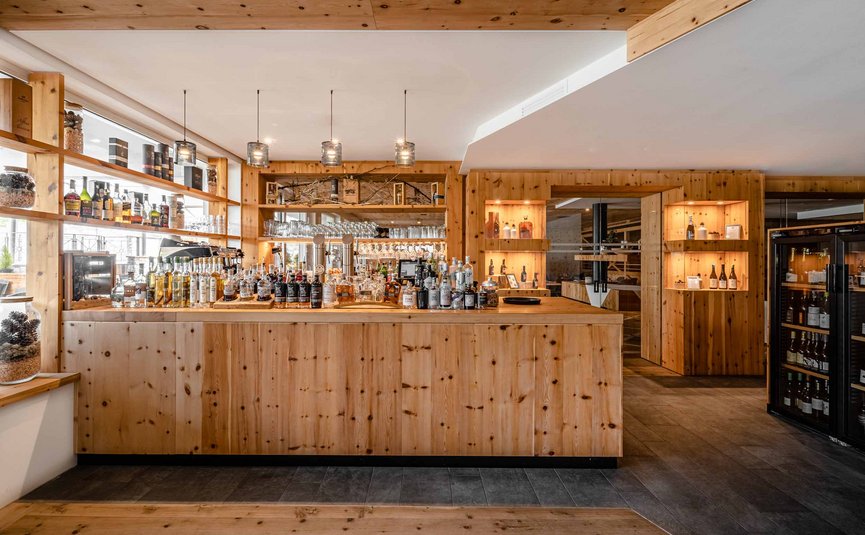 Bar moderna in legno con bottiglie e bicchieri, interno caldo e illuminato