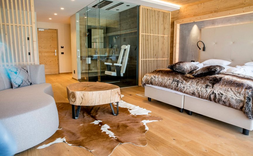 Modernes Hotelzimmer mit Holzmöbeln, Fellteppich und Glasbad