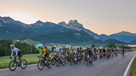 Viele Radfahrer fahren auf einer Landstraße mit Bergen im Hintergrund